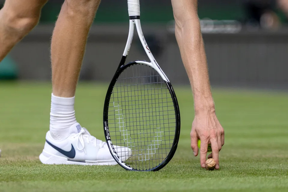 LONDON, ENGLAND - JULY 13: Jannik Sinner of Italy picks up a popped champagne cork which landed on the court during his match against Carlos Alcaraz of Spain in the Gentlemen's Singles Final on Centre Court during the Wimbledon Lawn Tennis Championships at the All England Lawn Tennis and Croquet Club at Wimbledon on July 13th, 2025, in London, England. (Photo by Tim Clayton/Getty Images)