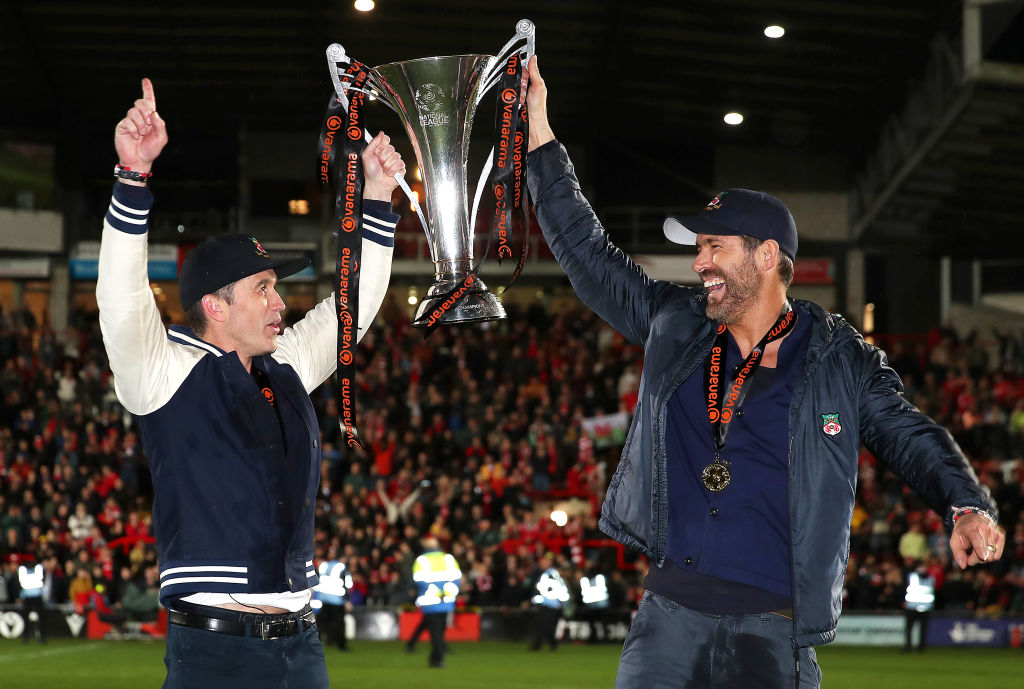 Rob McElhenney and Ryan Reynolds, Owners of Wrexham celebrate with the Vanarama National League trophy as Wrexham win the Vanarama National League and are promoted to the English Football League after victory in the Vanarama National League match between Wrexham and Boreham Wood at Racecourse Ground on April 22, 2023 in Wrexham, Wales.
