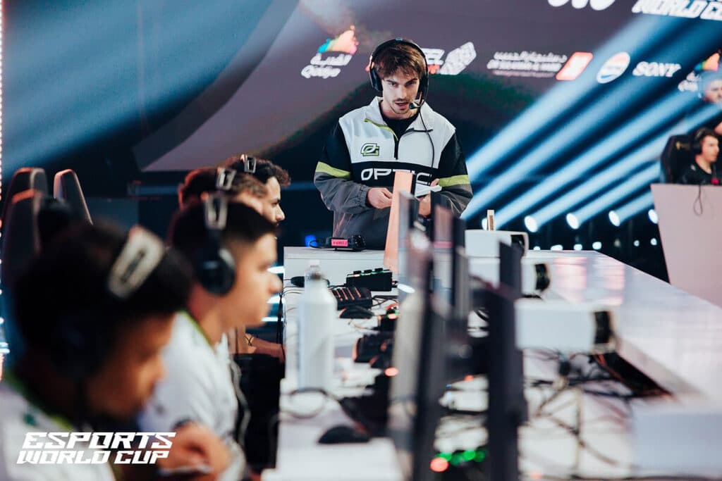 Image of OpTic Gaming competing at Esports World Cup. The team's coach is standing at the end of the stage.