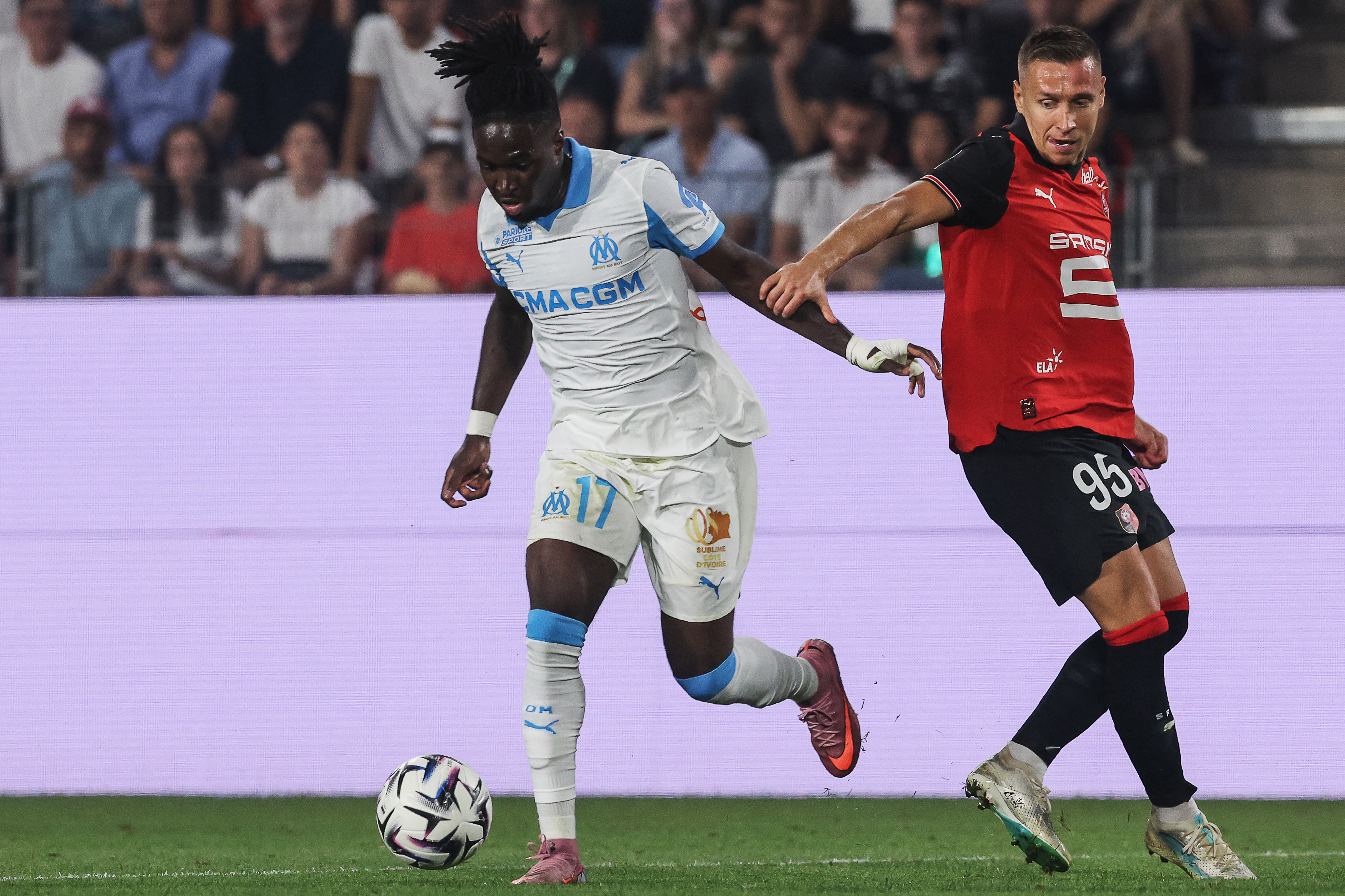 Marseille's English forward #17 Jonathan Rowe (L) controls the ball next to Rennes' Polish defender #95 Przemyslaw Frankowski during the French L1 football match between Stade Rennais FC and Olympique de Marseille (OM) at Roazhon Park stadium in Rennes, western France, on August 15, 2025. (Photo by FRED TANNEAU / AFP)