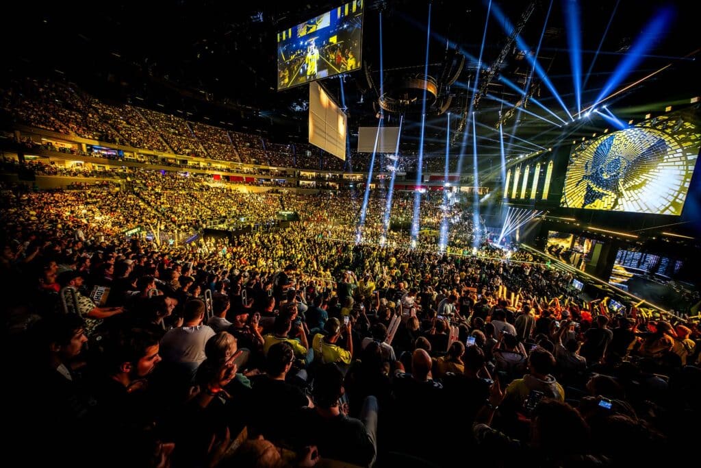 Image of IEM Cologne 2025 stage illuminated with yellow lights. The Team Vitality logo is displayed on the screens above the stage