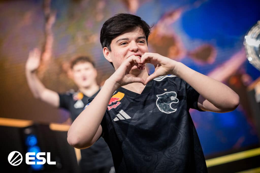 Image of FURIA Counter-Strike player Molodoy making a heart shape with his hands while teammates celebrate in the background