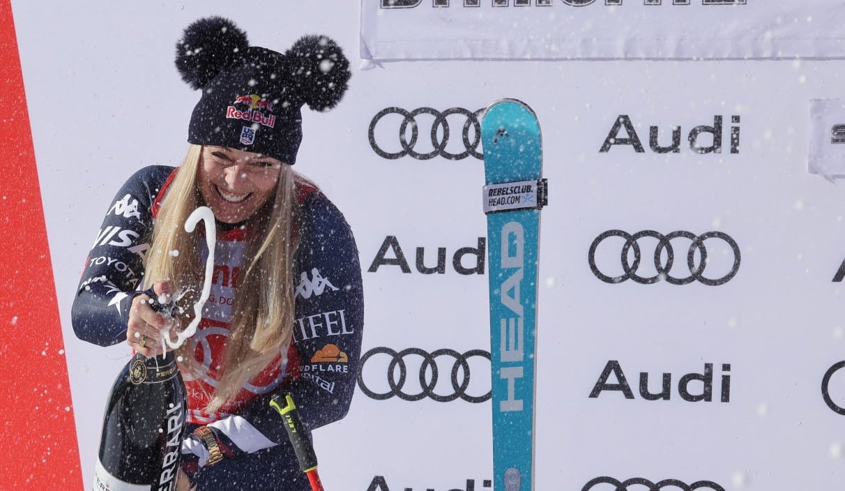 A women's skier pops a bottle of champagne.