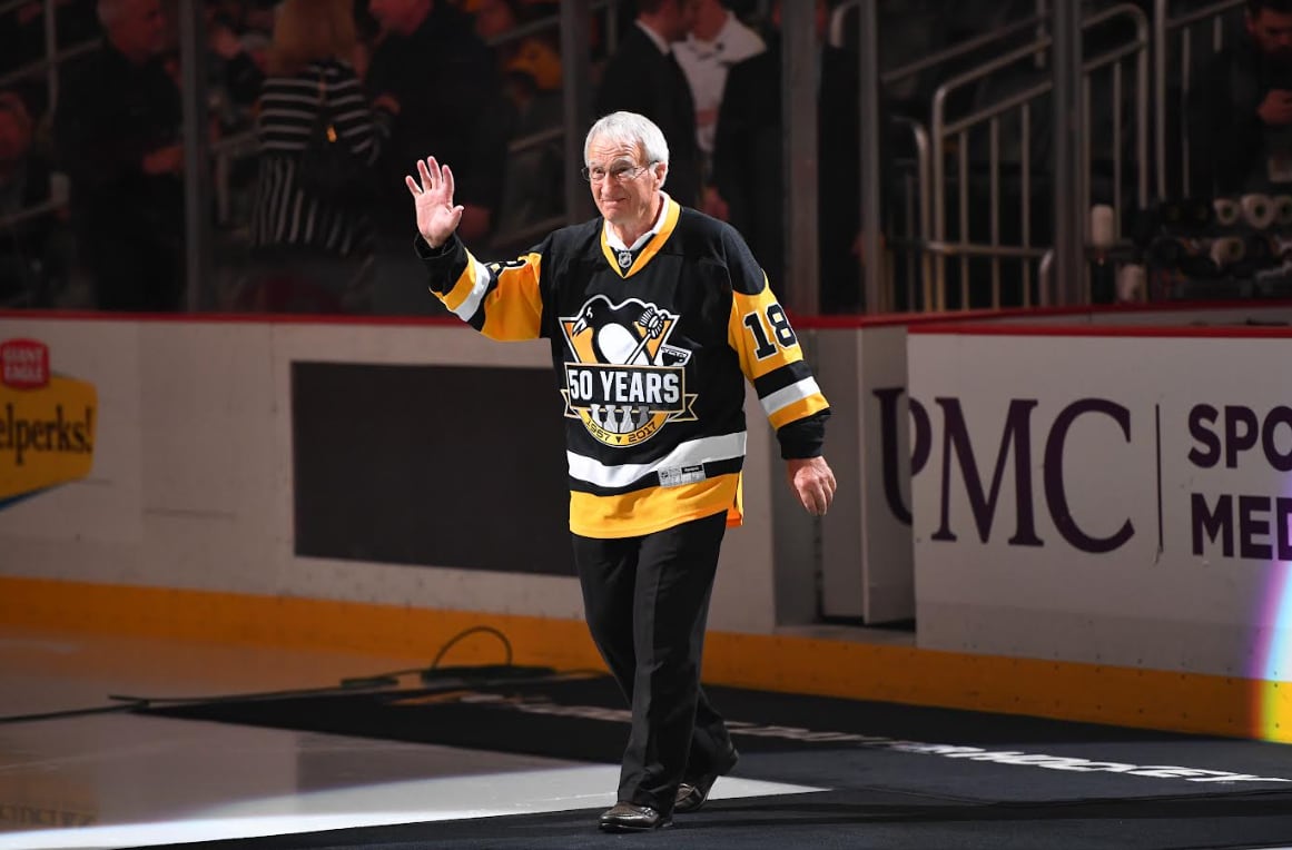 A man walking on an ice rink with hockey jerseys