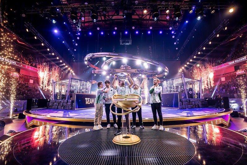 Team Falcons Dota 2 squad at Barclays Arena in Germany, raising the trophy for The International 2025