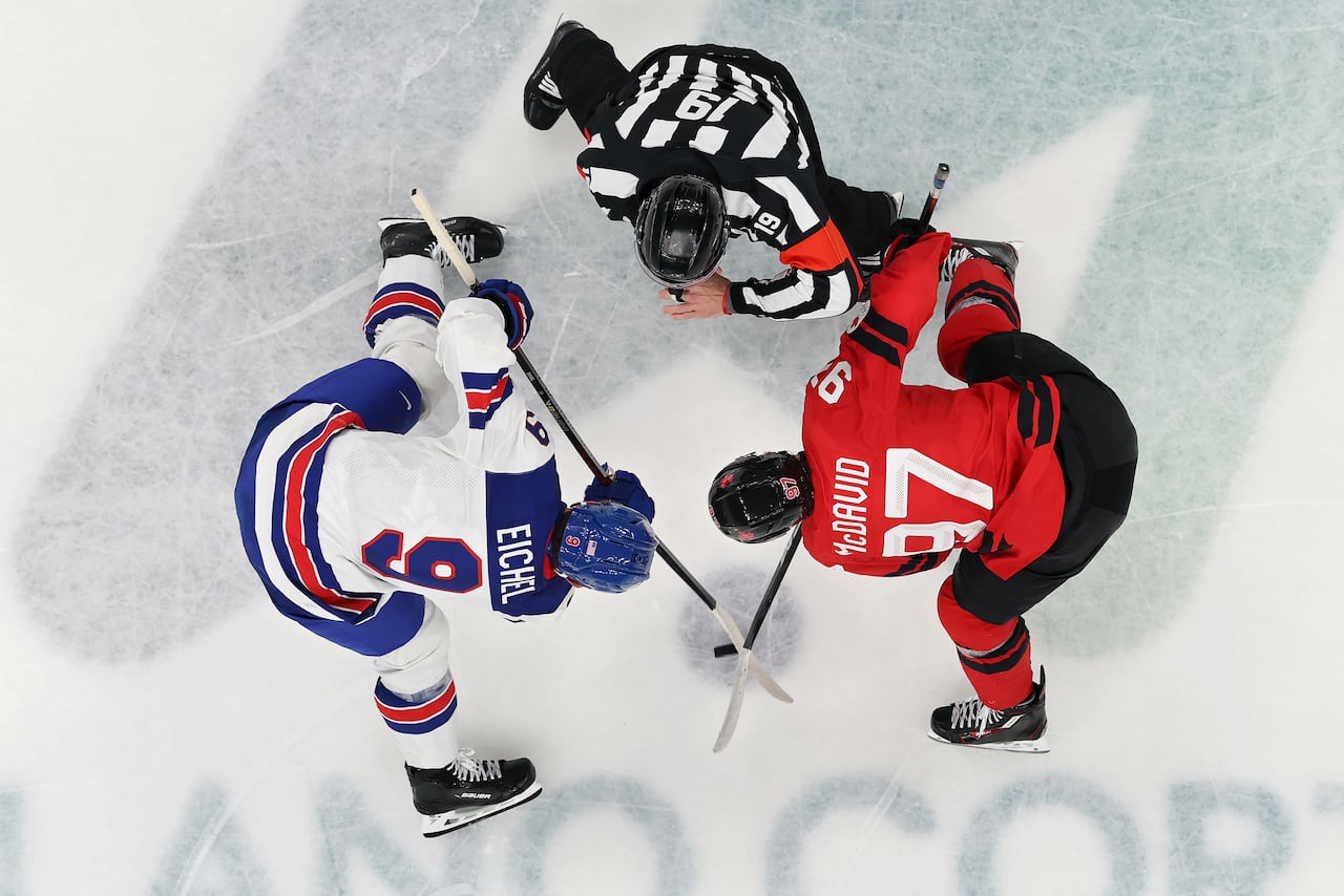Two hockey players representing Canada and the U.S. line up for a face-off.