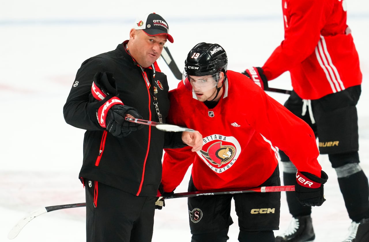 A hockey coach and player representing the Ottawa Senators discuss.