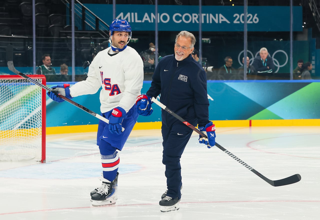 A men's hockey player skates with a coach.