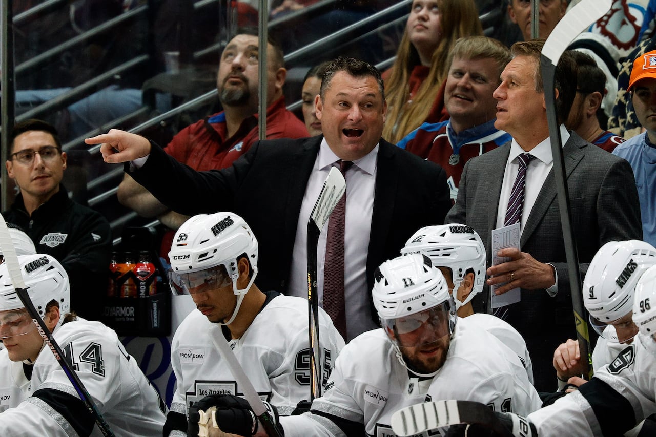 An assistant hockey coach gestures at his players.