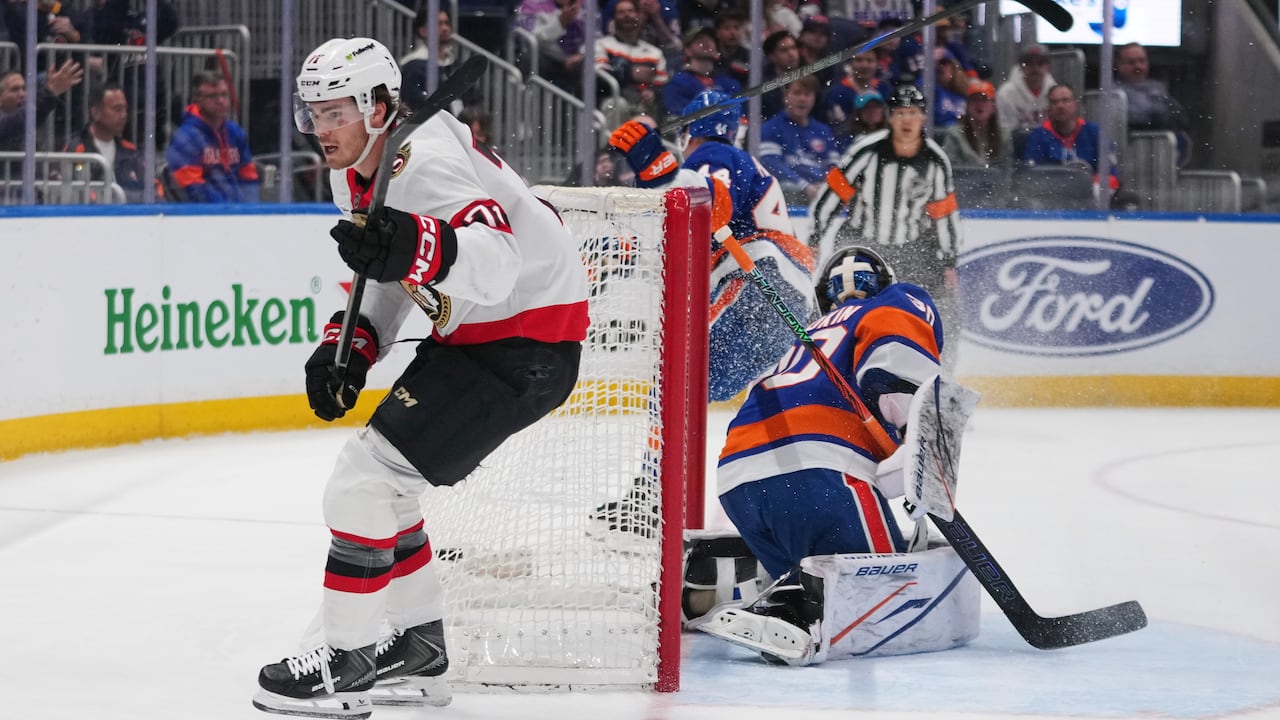 An ice hockey player glides beyond the rival team's netminder after successfully netting a point.