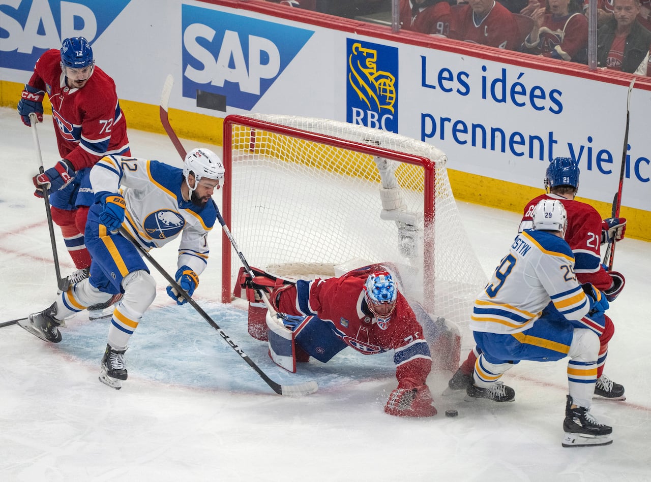 People around the net on a hockey surface.