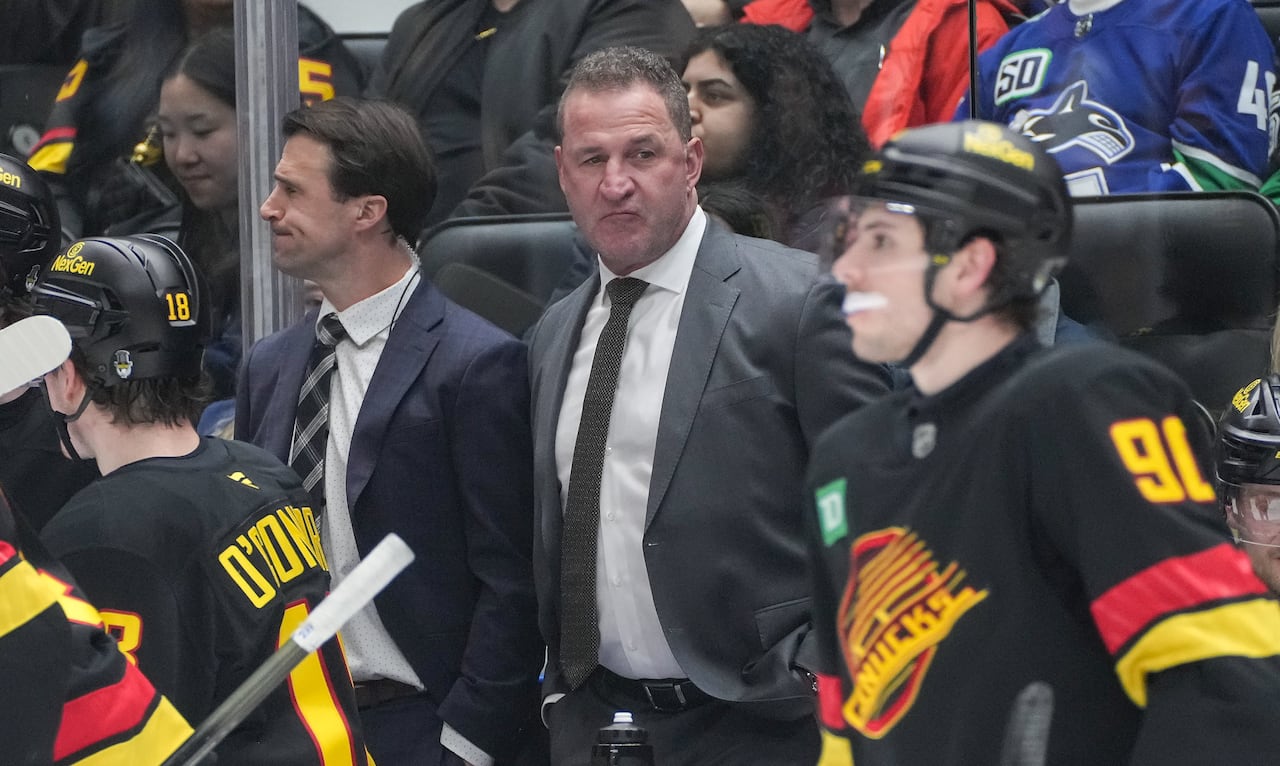 Vancouver Canucks' head coach Adam Foote (rear right) and assistant coach Brett McLean (rear left) observed from the bench during the second period of an NHL game facing the Vegas Golden Knights, held in Vancouver, on Tuesday, April 7, 2026.