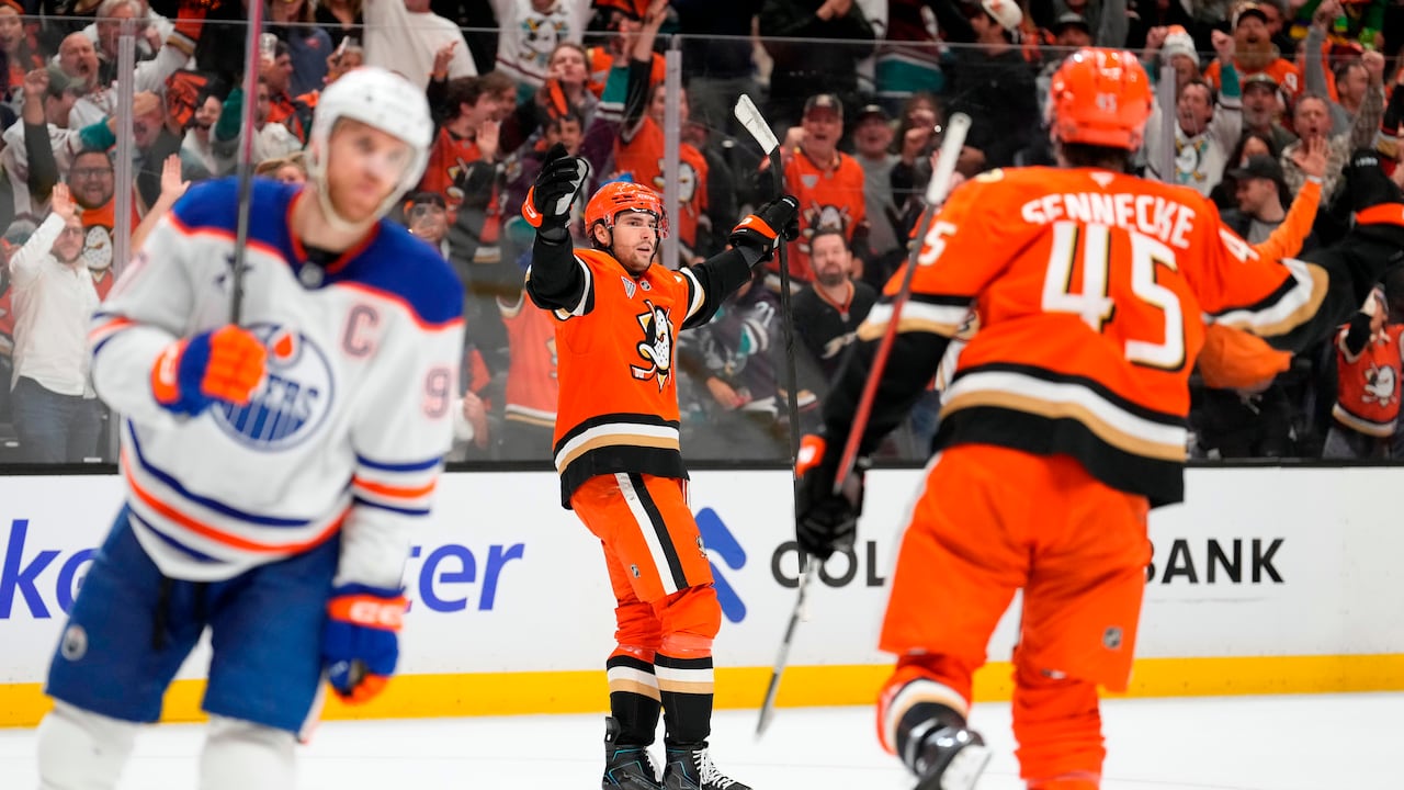 Two hockey players wearing orange jerseys celebrate a goal.