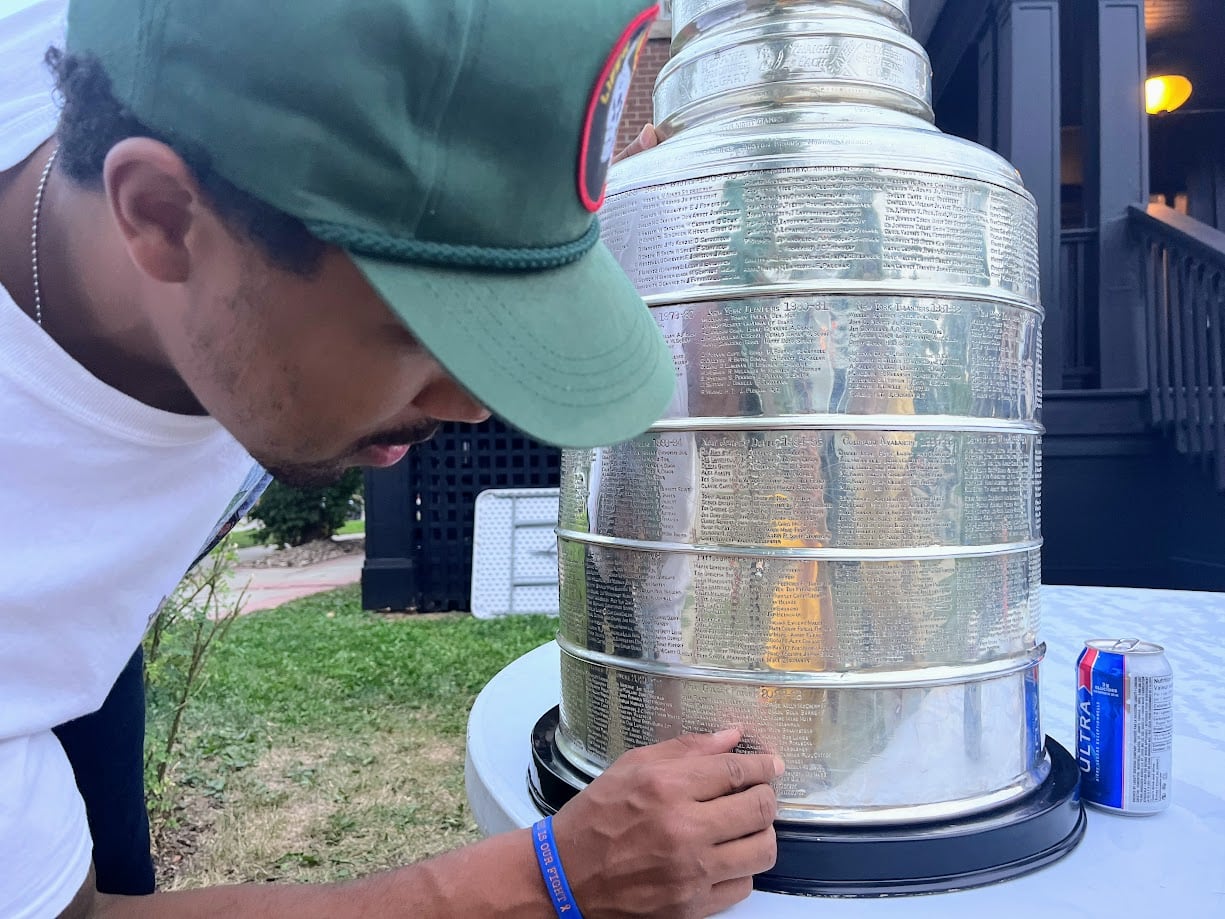 A man bends down to read engravings on a silver trophy.