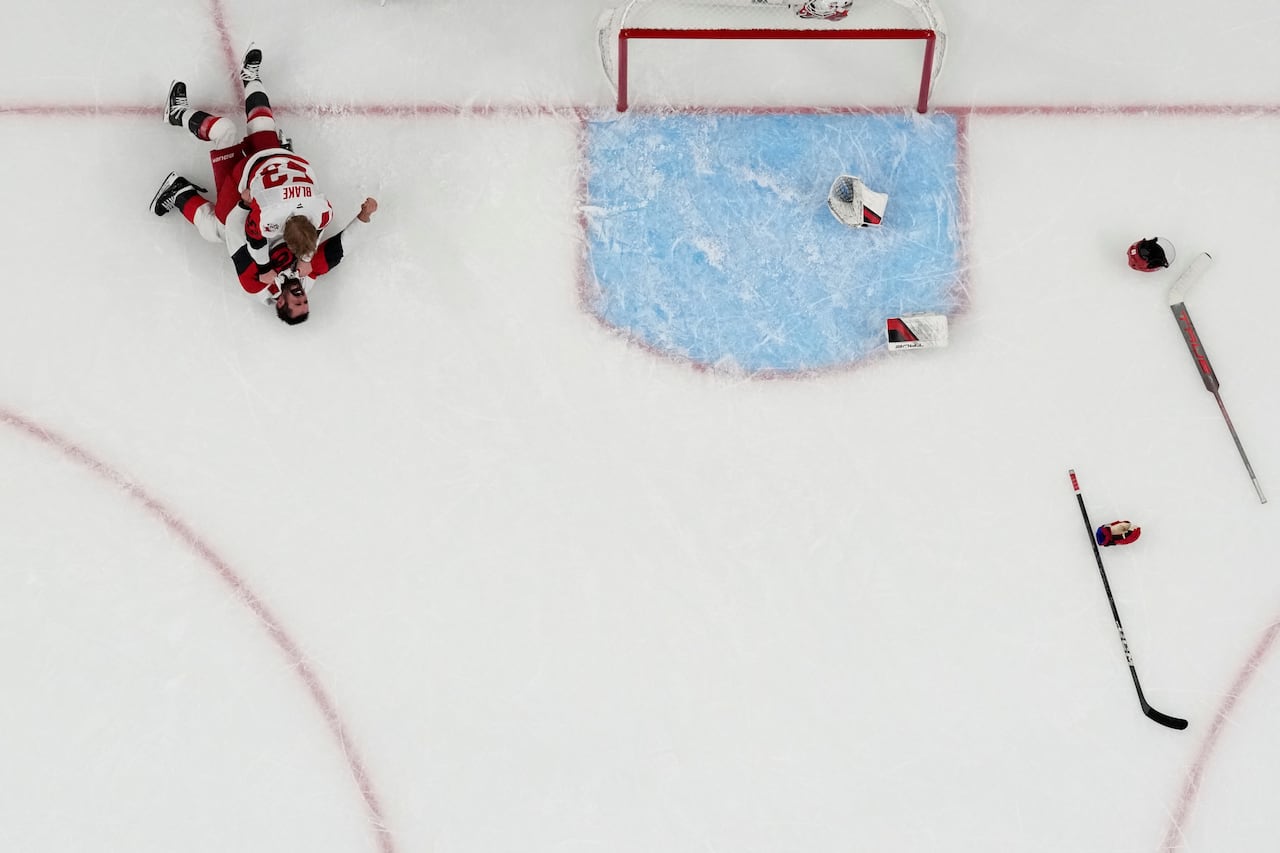 Two hockey players lie on the ice in celebration after winning a championship. They're seen from above, in an aerial image.