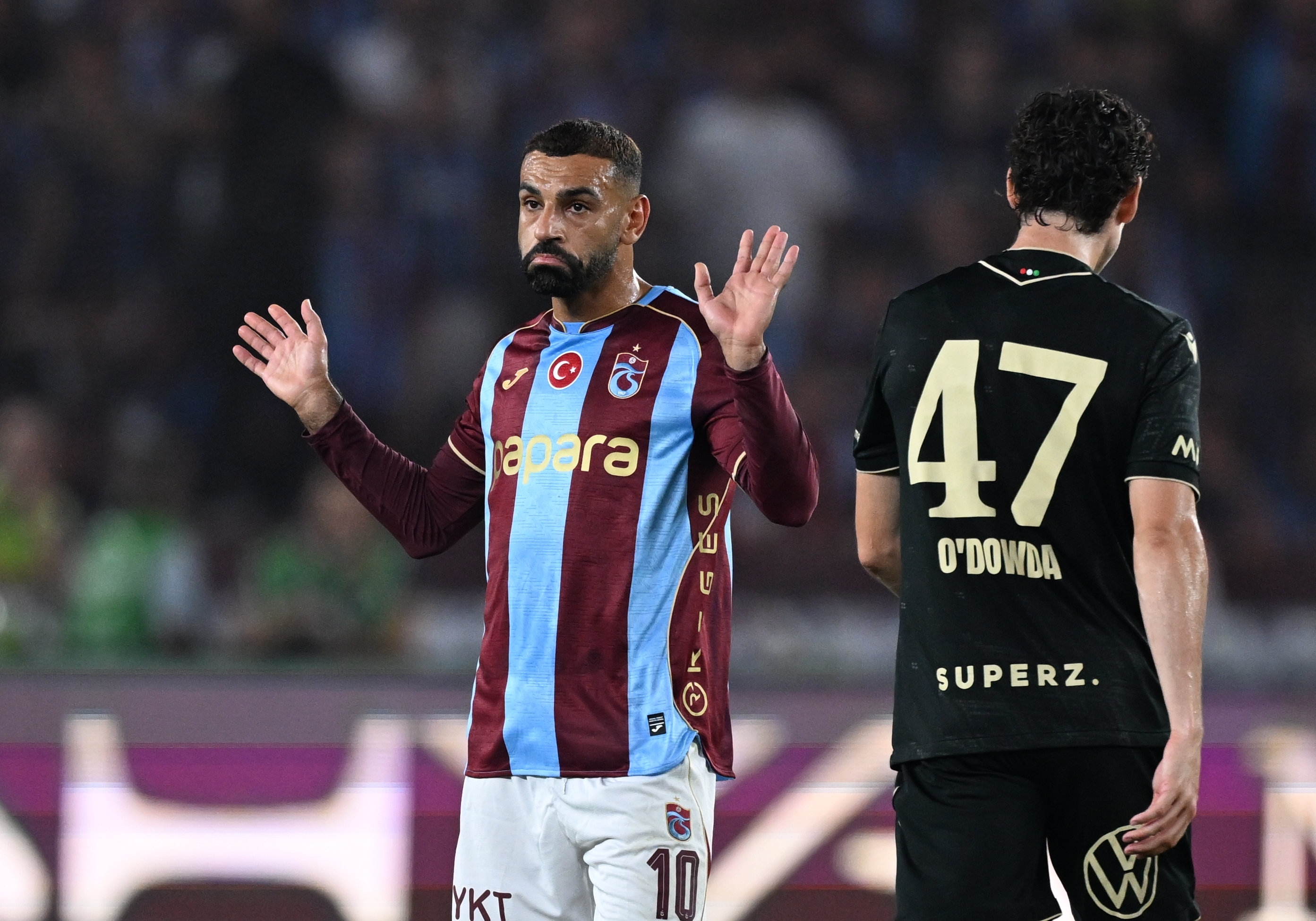 Mohamed Salah raising his hands while sporting a Trabzonspor jersey.