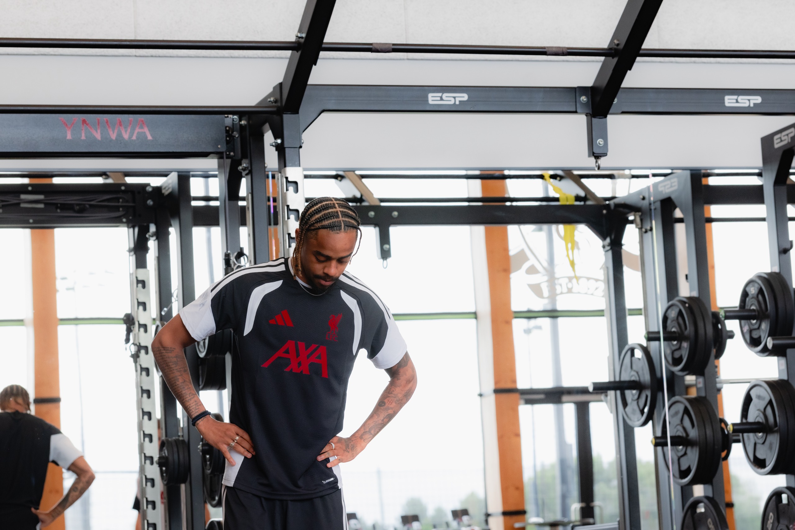 Bradley Barcola in the Liverpool training ground's gym. Hands on hips, looking at the floor.