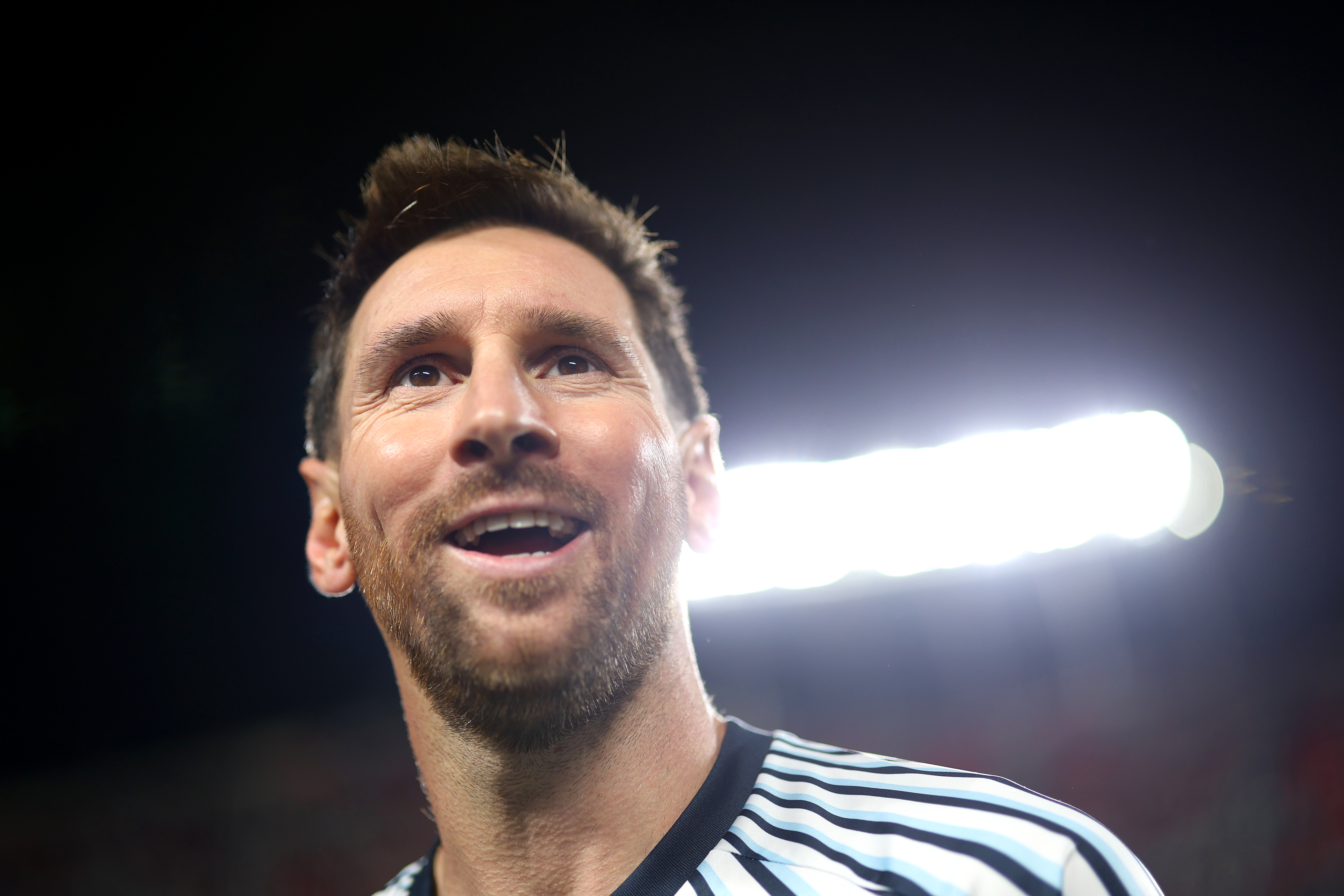 Close-up of Messi smiling. Camera angled up, from below.
