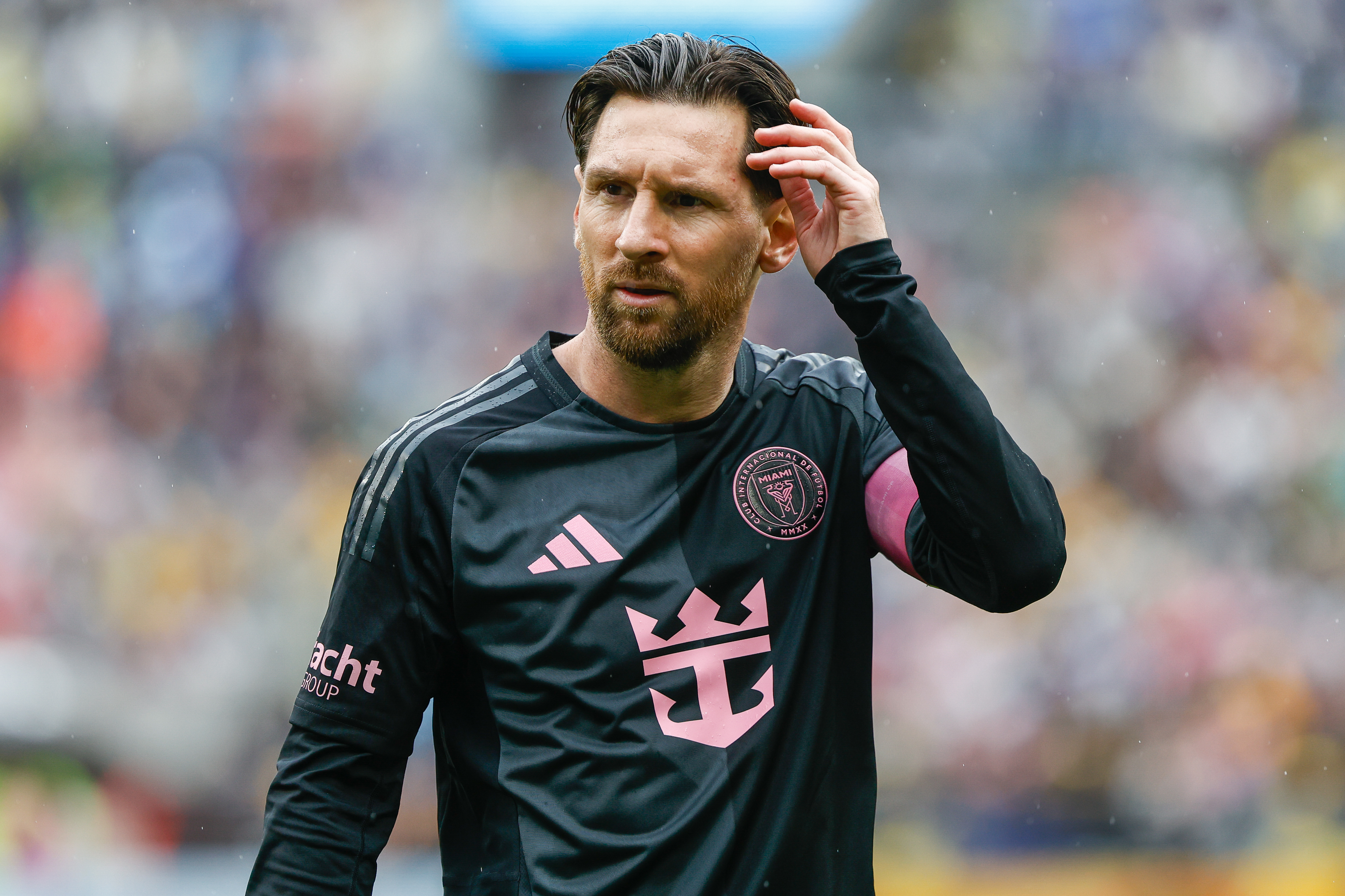 Lionel Messi adjusting his hair while wearing an Inter Miami jersey.
